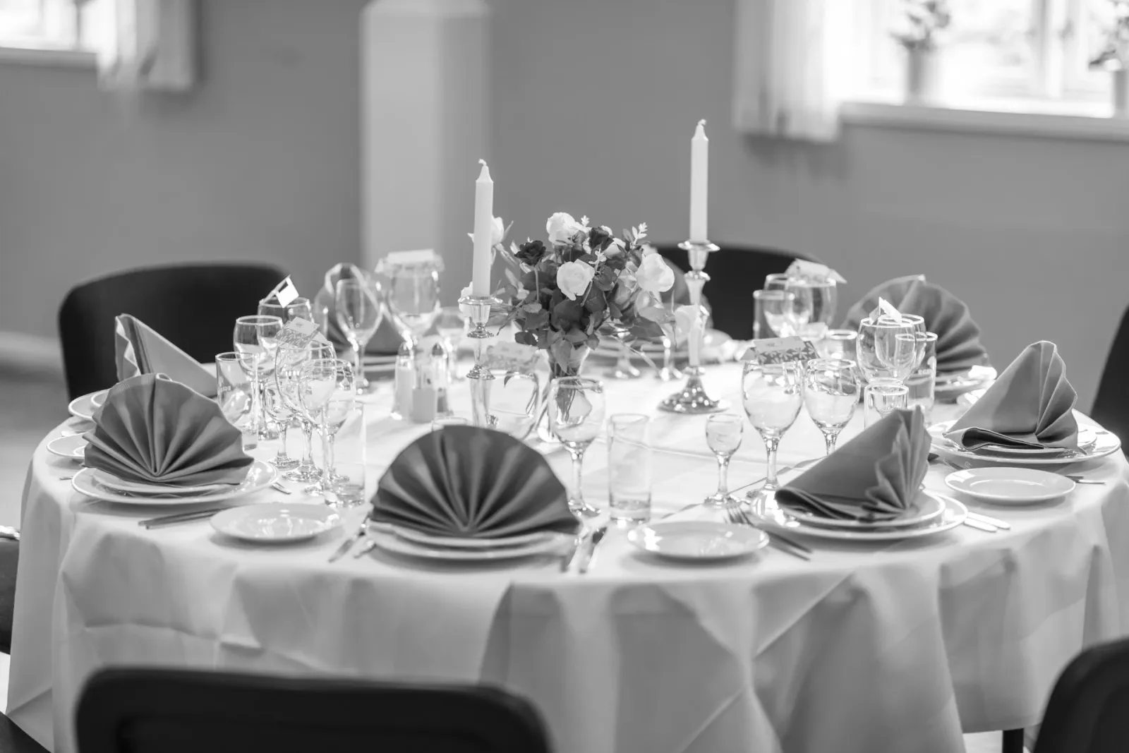 Festligt dækket bord med glas, servietter og blomster, sort/hvid